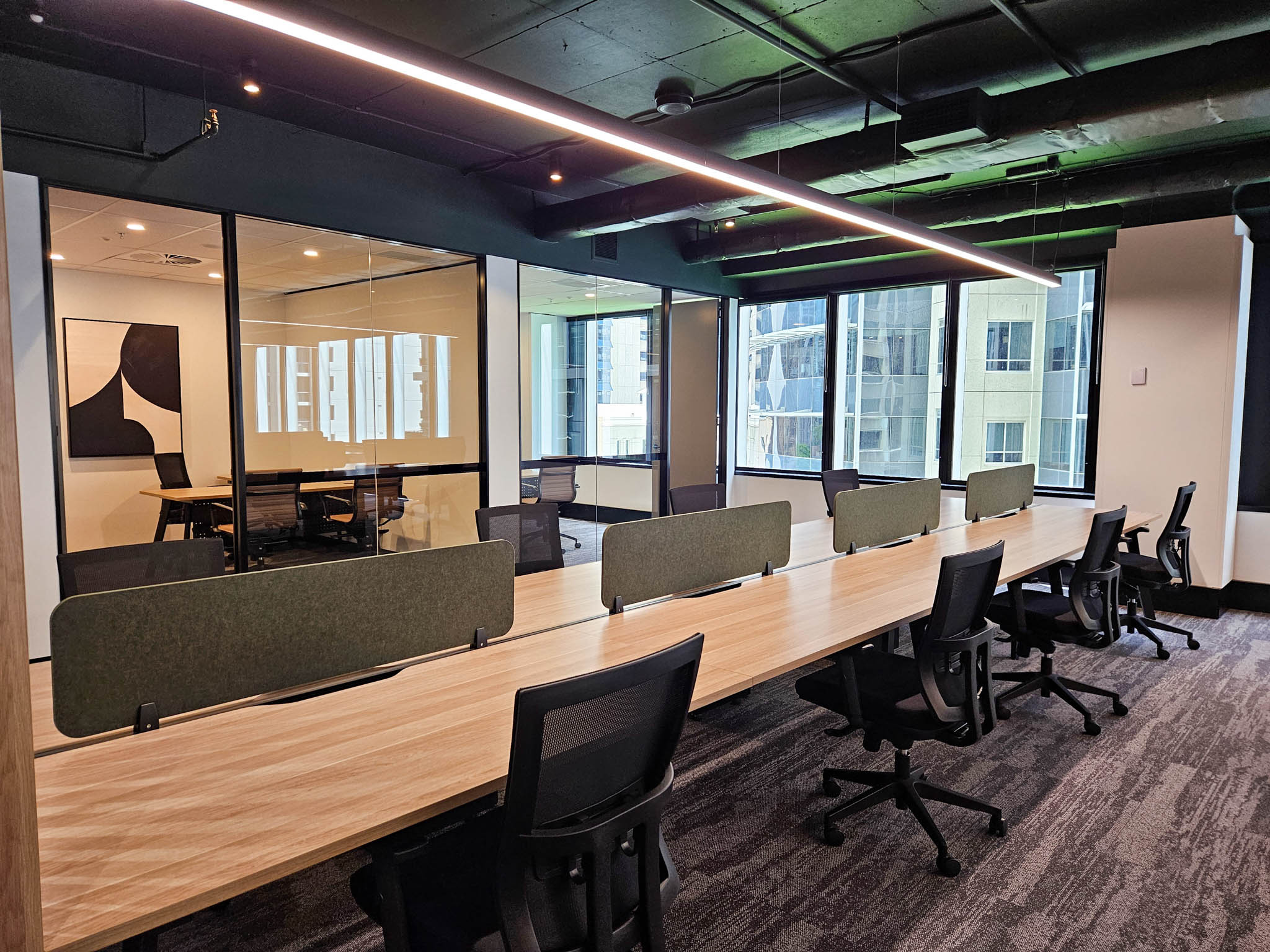 Office interior with workstations, chairs, and green acoustic screens