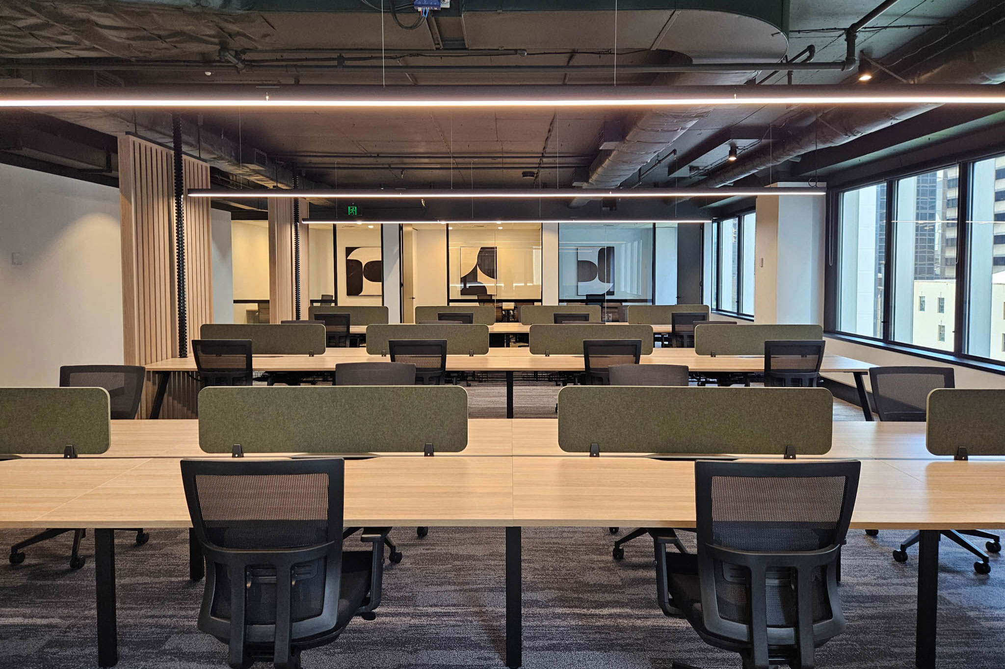 Office interior with workstations, chairs, acoustic screens, and private offices in background