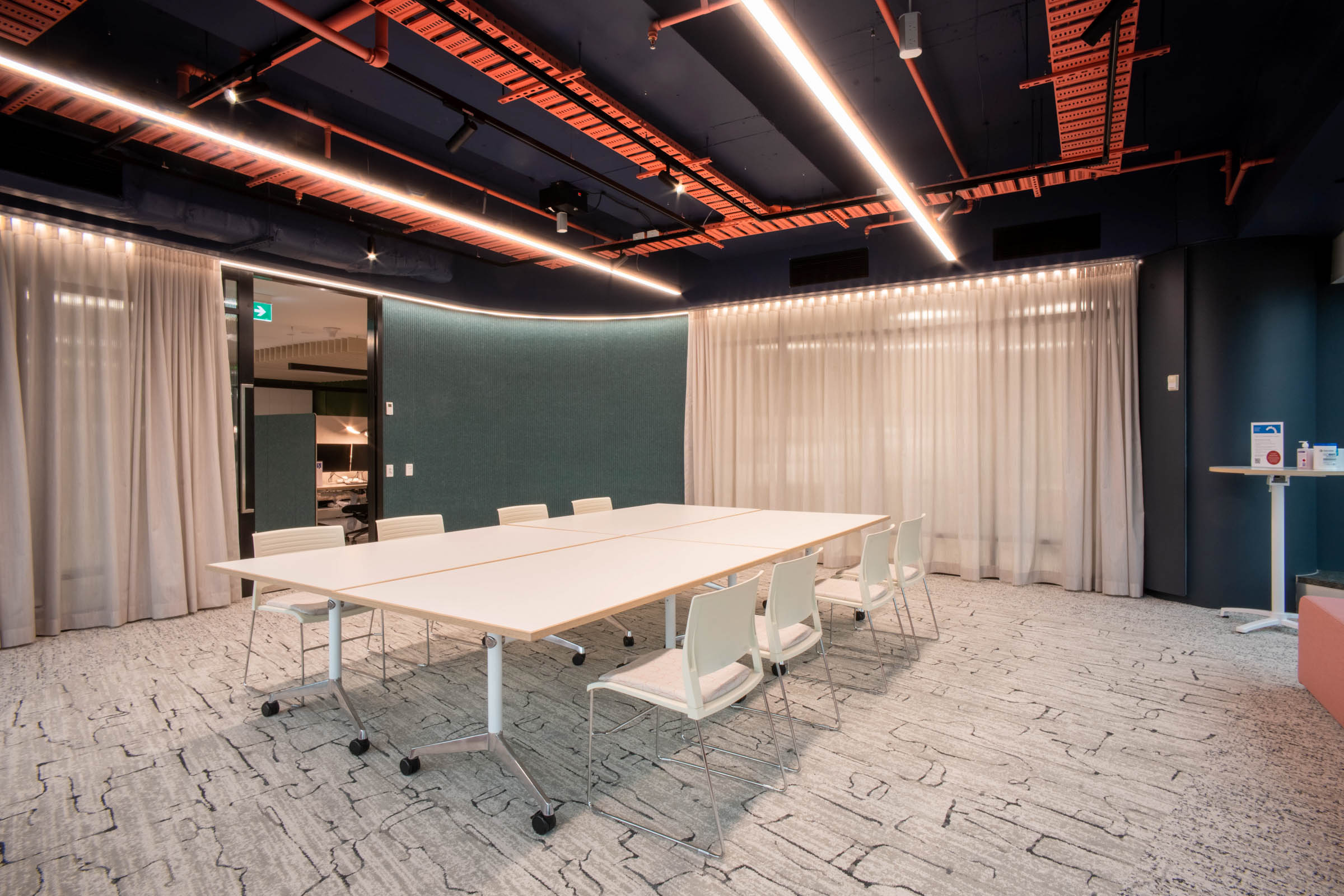 Commercial meeting room with white tables and acoustics on walls