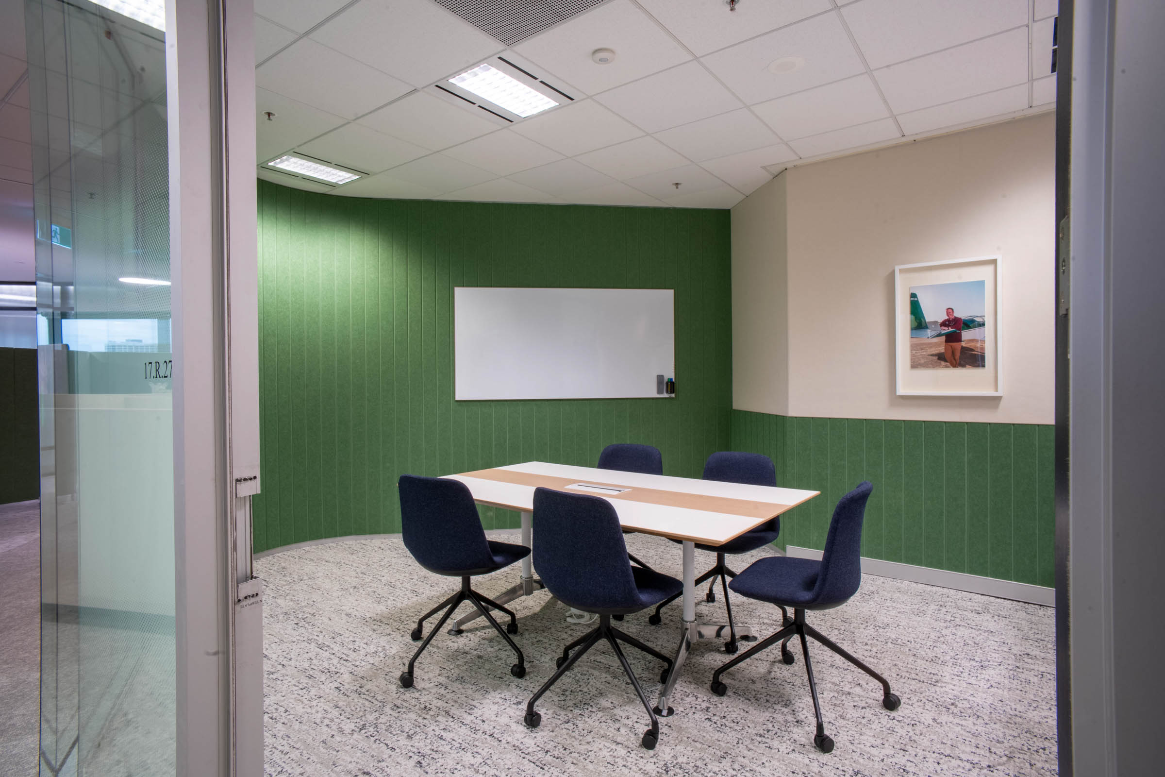 Green grooved acoustics in small meeting room with blue chairs